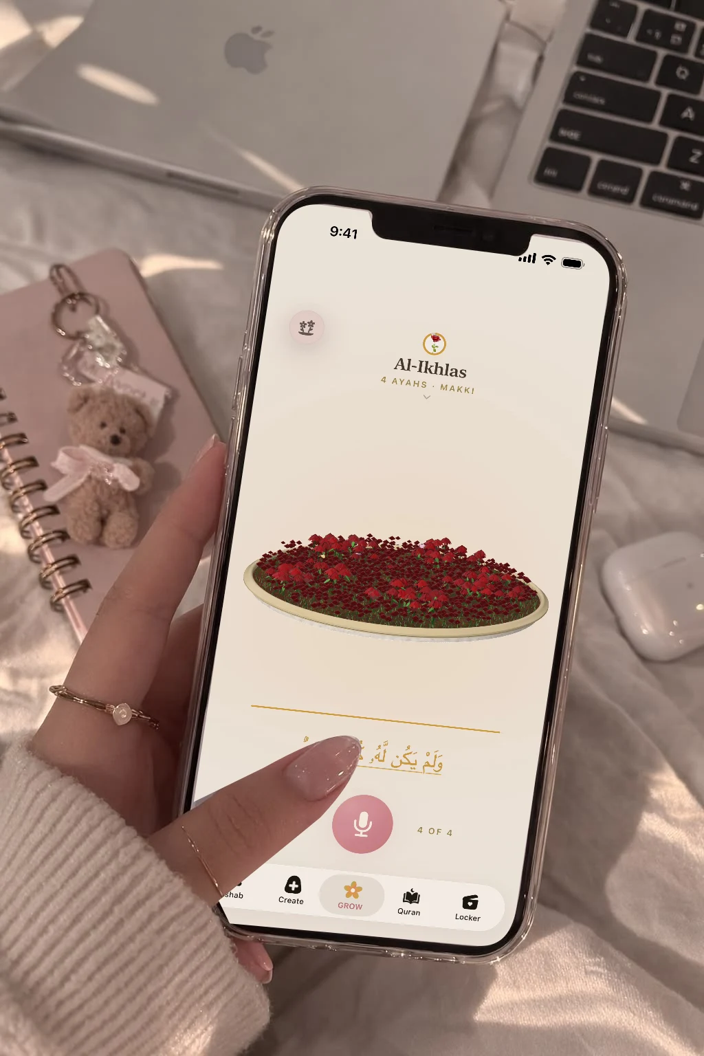 A Hablobi screen composited into a handheld phone on white bedding beside a pink notebook.
